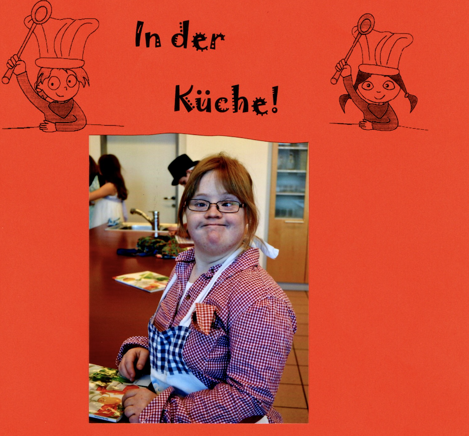 Bild von Hanna auf rotem Hintergrund. Hanna trägt eine Brille, ein kariertes Hemd und eine Kochschürze. Sie steht an einer roten Kochplatte