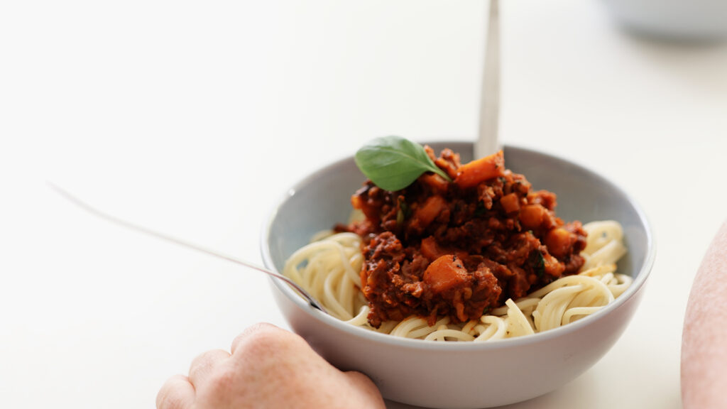 Das Foto zeigt eine vegan Pasta Schutta. in einer Schüssel. Das Gericht ist mit einem Basilikumblatt garniert.